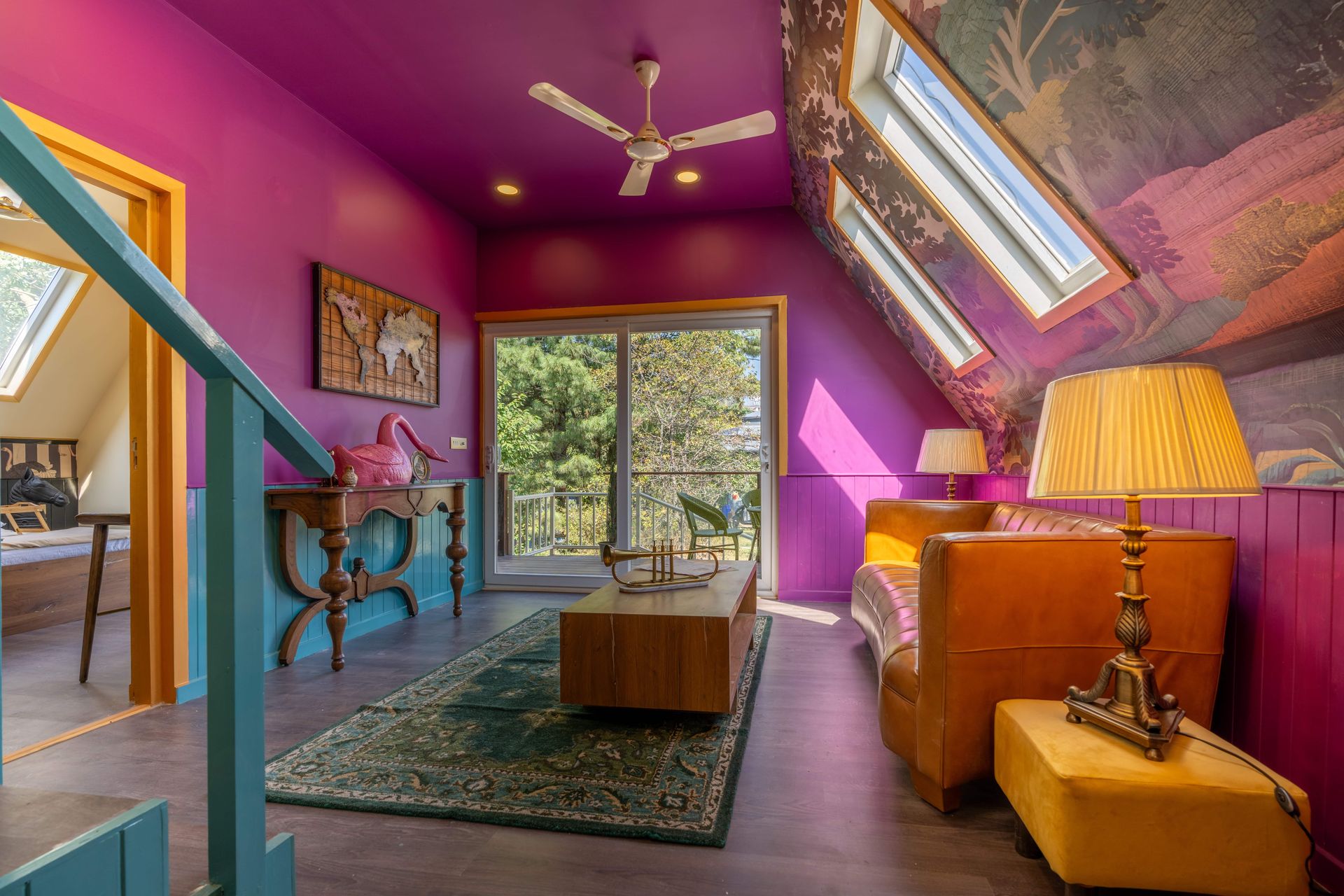 Stylish attic room with purple walls, leather sofa, and large windows.